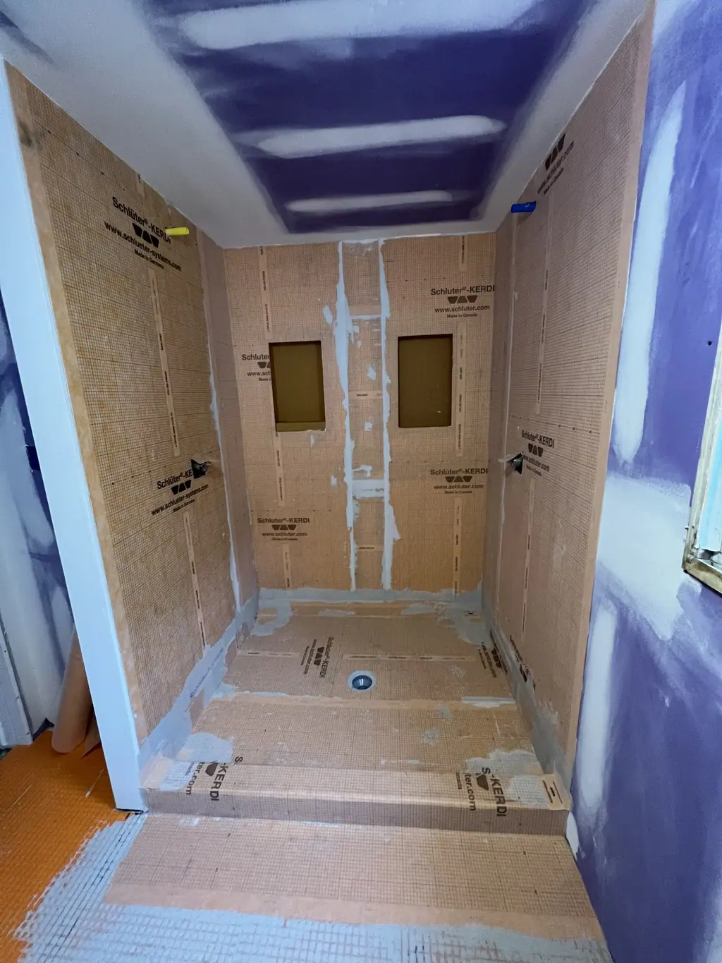 Same tub alcove before tile, with waterproofing membrane and niches framed