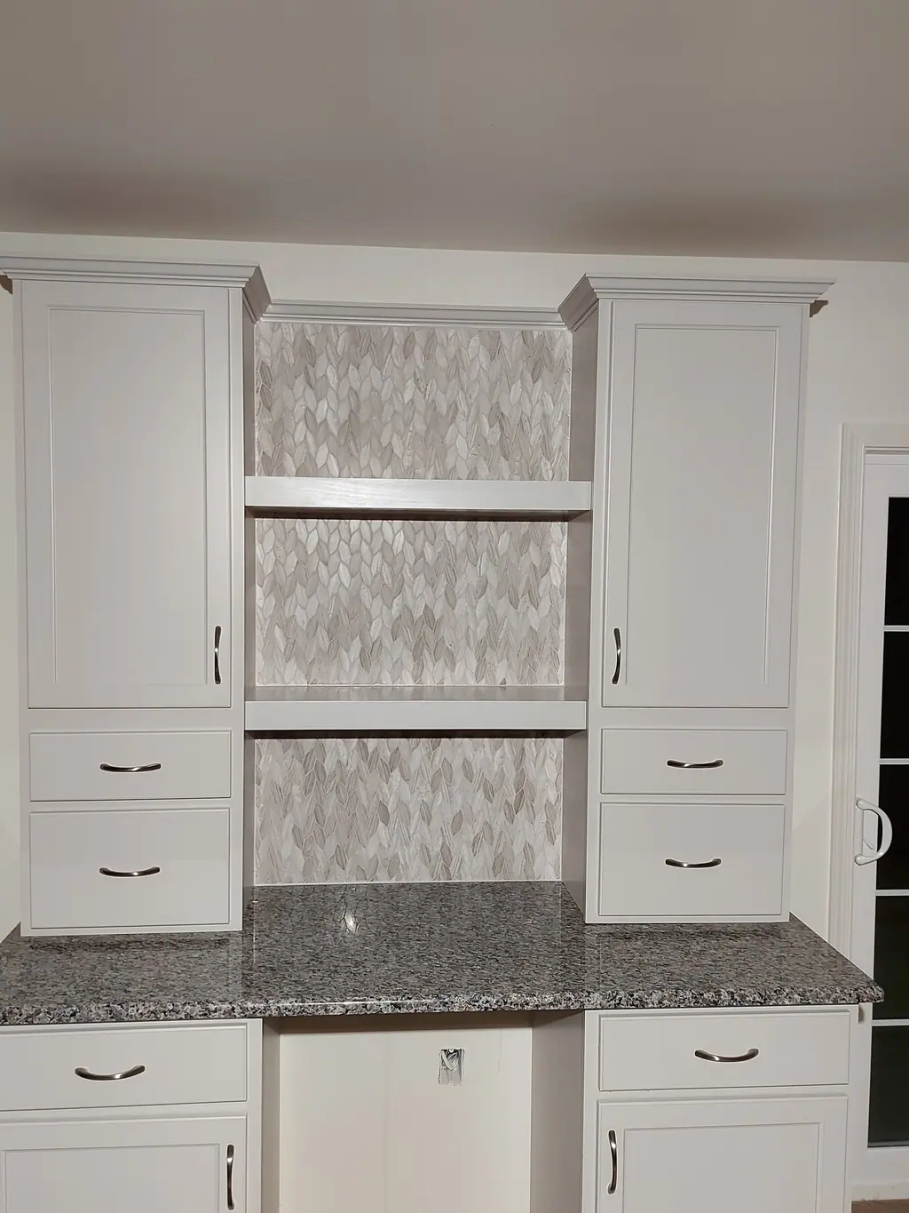Built-in cabinetry with marble herringbone backsplash panel