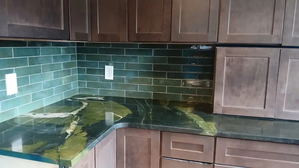 Green glazed subway backsplash with green granite and dark cabinets