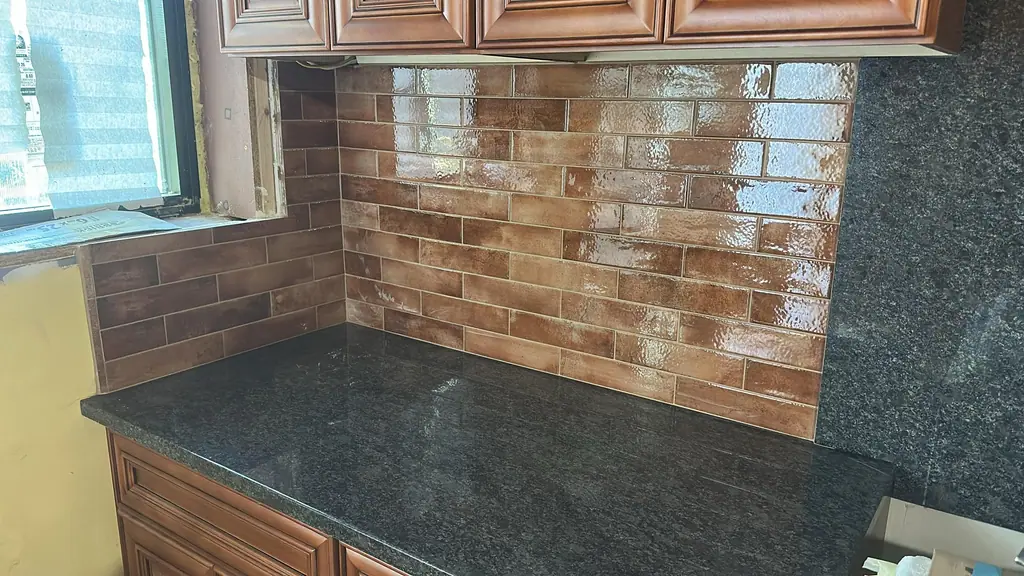 Terracotta brick-look backsplash above dark granite counters