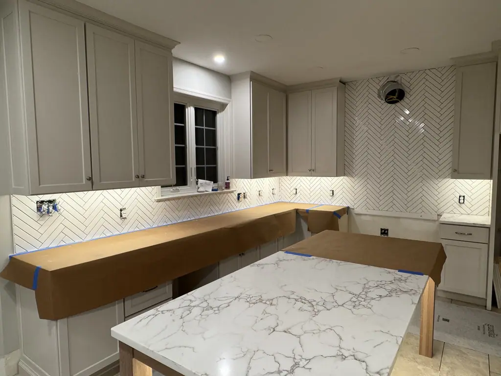 White herringbone backsplash with quartz island in a new kitchen