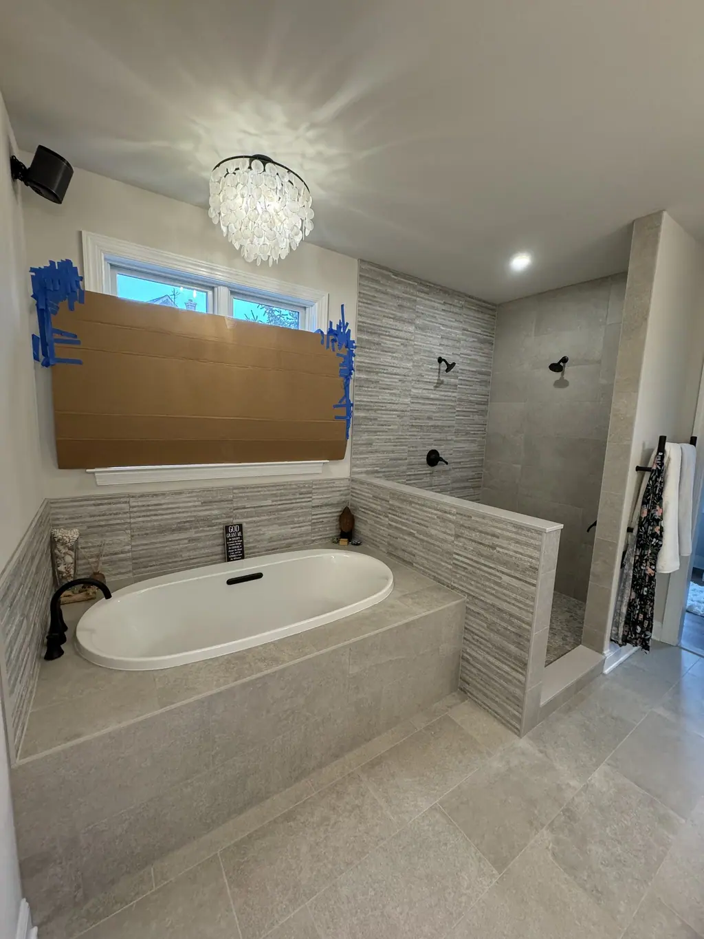 Primary bathroom with freestanding-style soaking tub deck, linear tile and crystal chandelier