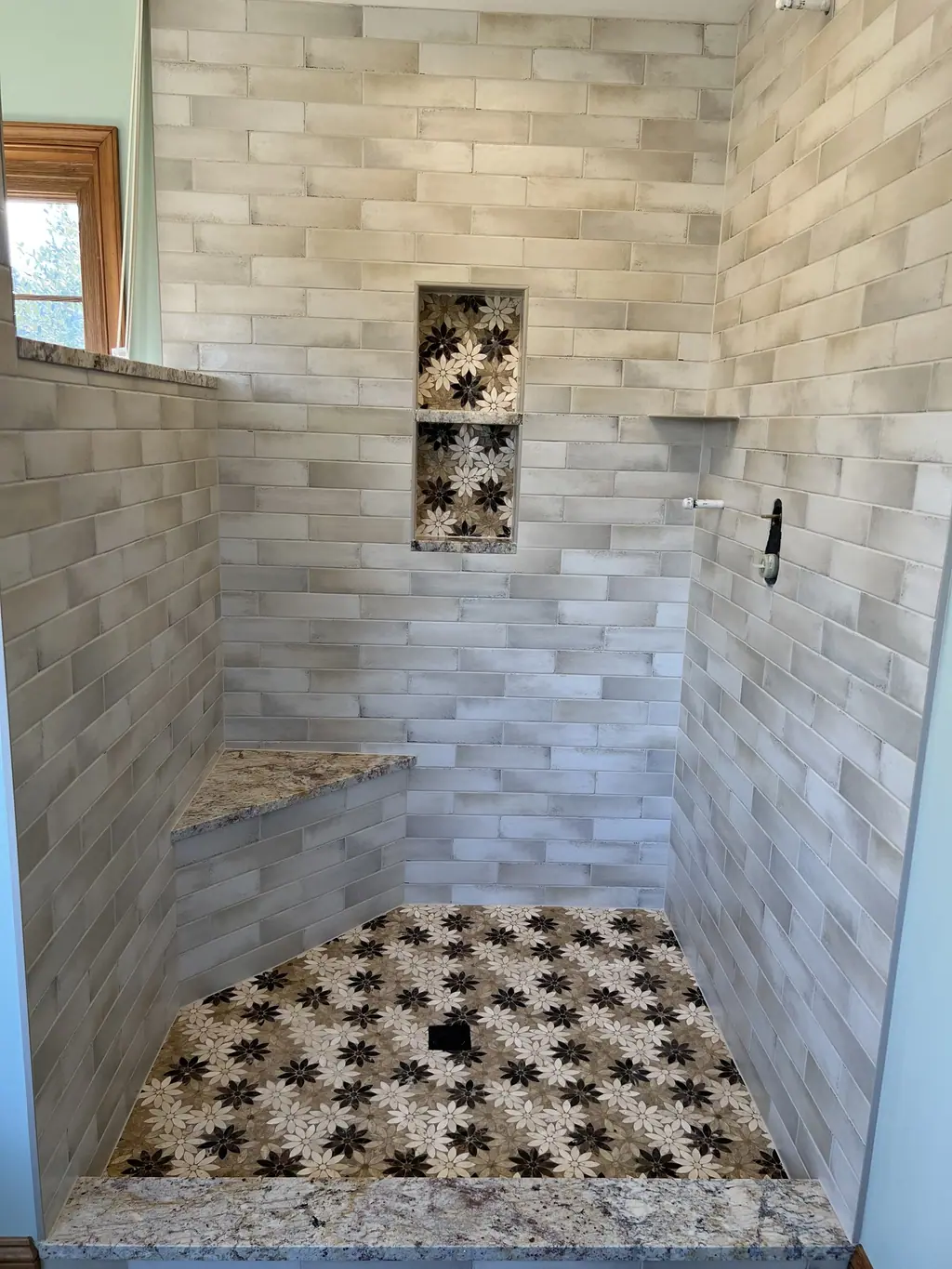 Shower with flower mosaic floor, matching niche and granite bench