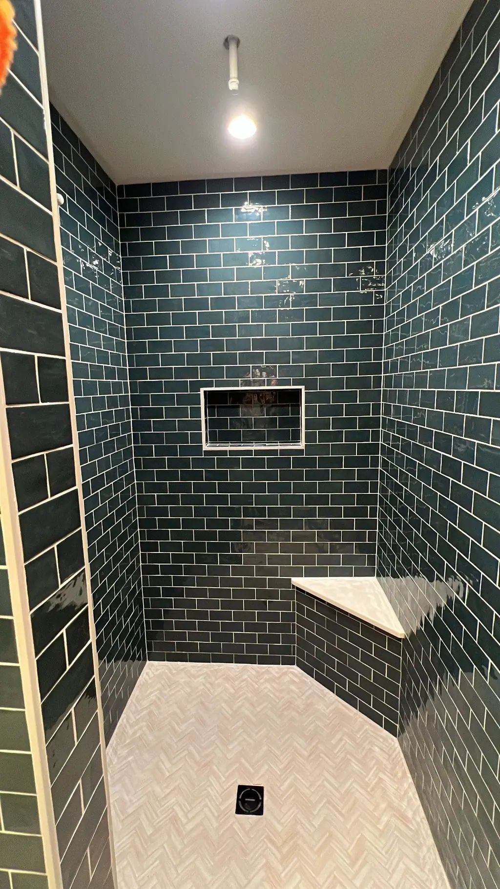 Navy glazed subway tile shower with recessed niche and corner bench