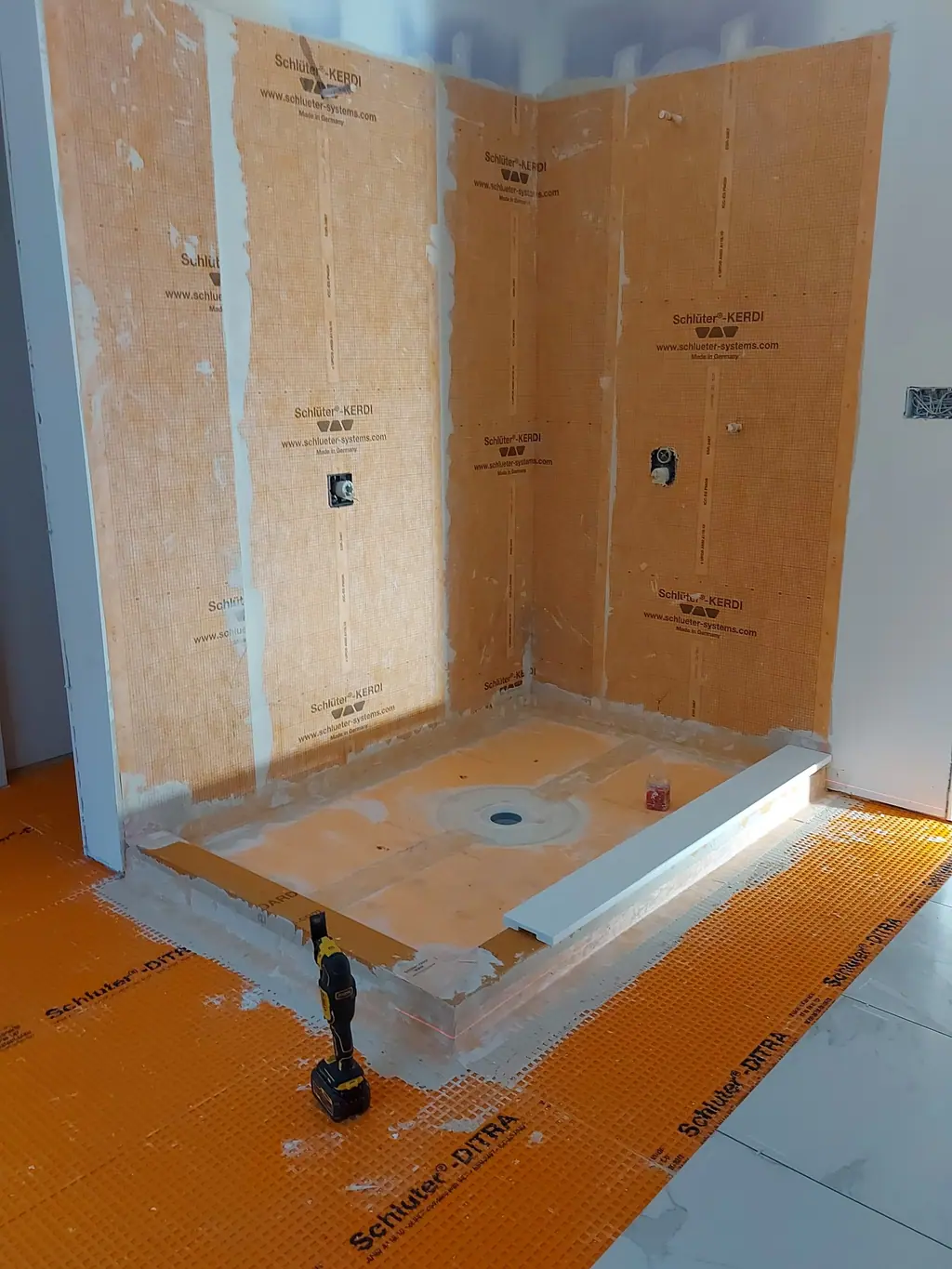 Shower pan and walls covered with orange waterproofing membrane
