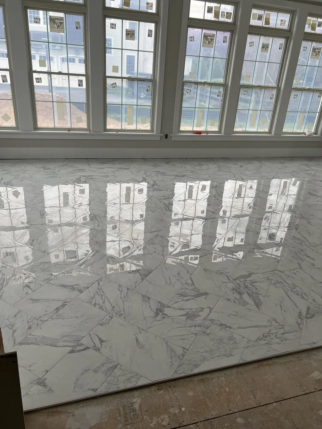 Large-format polished porcelain floor reflecting window light