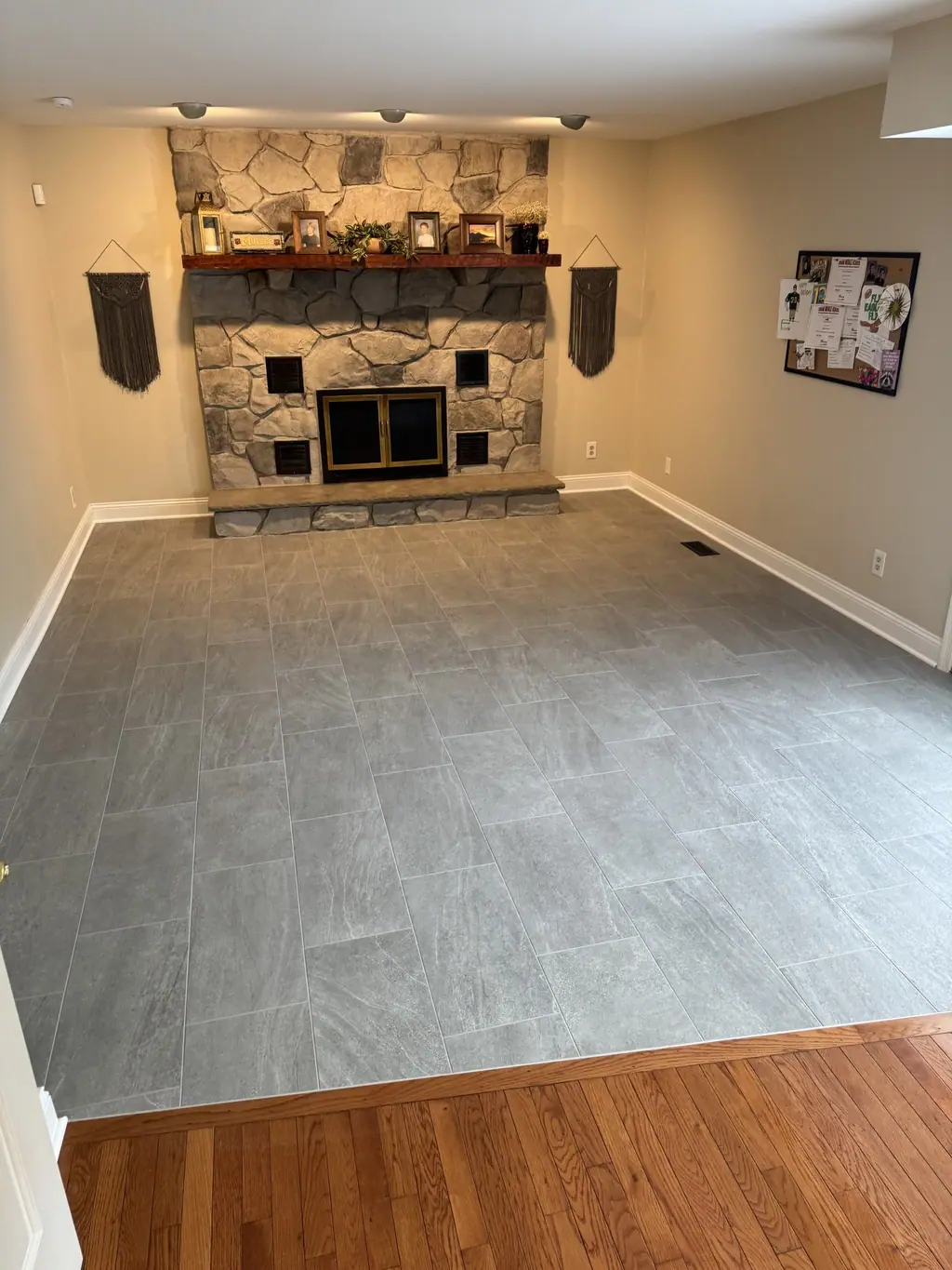 Gray plank porcelain floor in a family room with stone fireplace